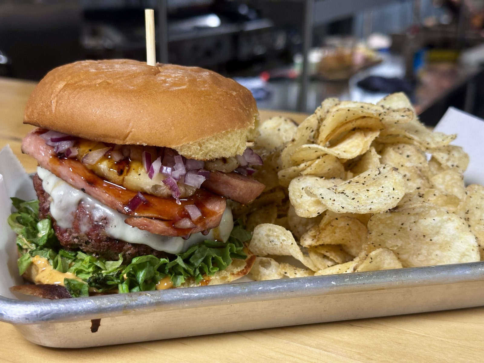 A grilled pineapple and ham burger build with kettle chips