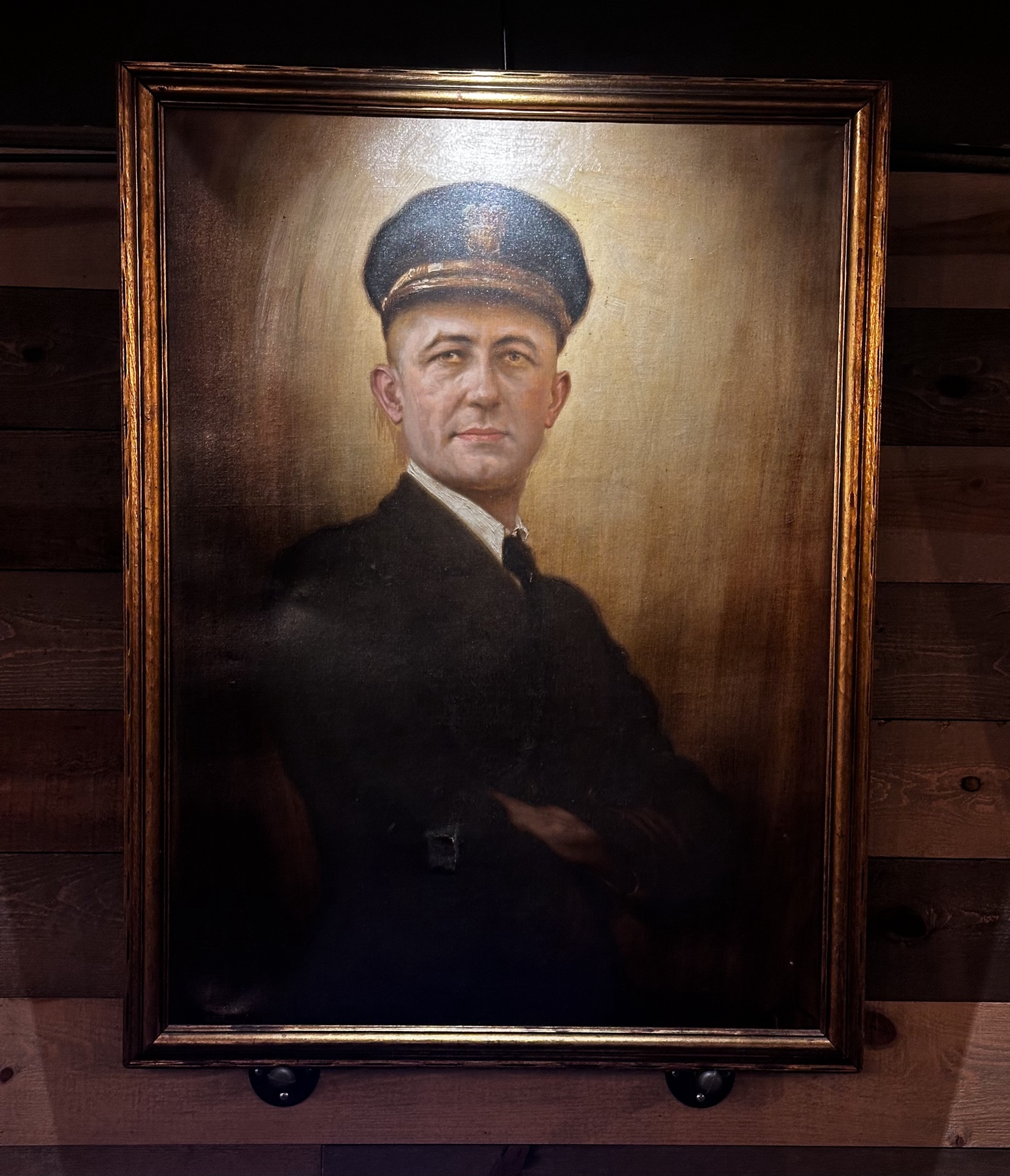 A framed oil painting of Commander Ralph Weyerbacher, hanging on the restaurant's wood-plank wall