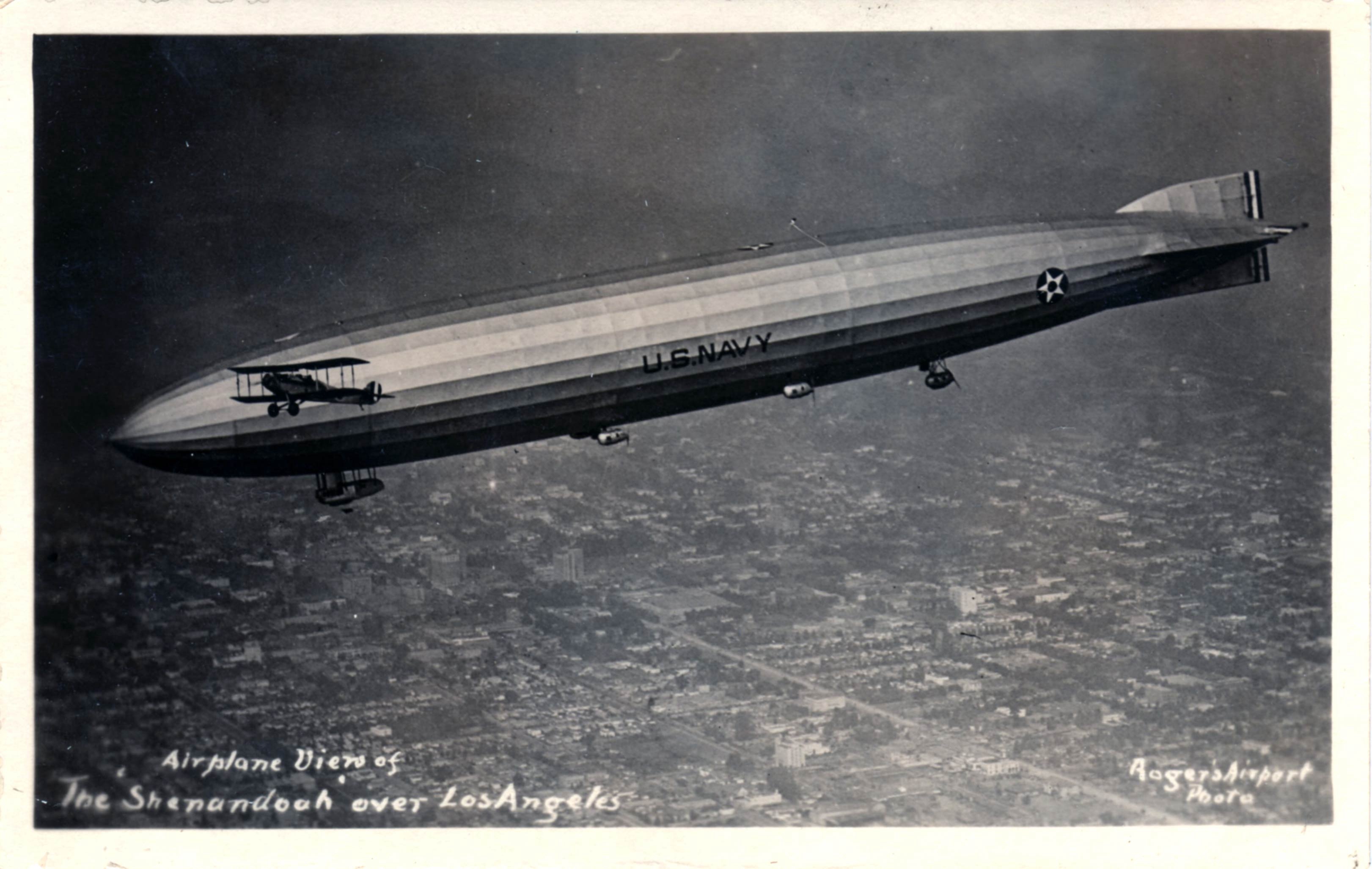 A vintage postcard photograph of the U.S. Navy airship Shenandoah flying over Los Angeles